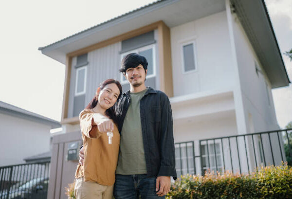 Asian young couple happy just received house key for their new house.